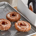 A tray of Pillsbury Old Fashioned Sour Cream cake donuts on a metal rack.