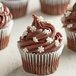 A chocolate cupcake with white snowflake sprinkles on top.