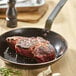 A steak cooking in a de Buyer Mineral B Element carbon steel fry pan on a table.