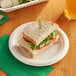 A sandwich on an EcoChoice natural bagasse plate with a salad and a drink.