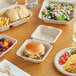 A table with EcoChoice bagasse plates, a wooden fork and knife, and a variety of food containers and utensils.