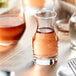 An Acopa glass carafe filled with liquid on a table.