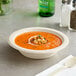 A bowl of soup with a wooden spoon on a napkin.