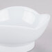 A white scallop shaped melamine bowl on a gray surface.