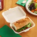 A sandwich in an EcoChoice Natural Bagasse take-out container on a table.