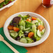 A plate of salad with a wooden fork on a table.