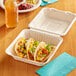 An EcoChoice bagasse take-out container with three tacos on a table.