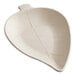 A white leaf shaped dish with a small leaf on it.