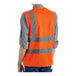 A person wearing a Lavex orange safety vest with reflective stripes.