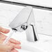 A person washing their hands with a Waterloo deck-mounted dual-sensor faucet.