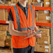 A man in an extra large orange surveyor's safety vest writing on a clipboard.