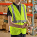 A man wearing a Lavex Class 2 lime high visibility safety vest writing on a clipboard.