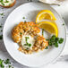 A plate of Mind Blown plant-based vegan crab cakes with lemon wedges and sauce.