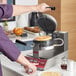 A person making waffles in a Estella commercial waffle maker.