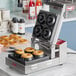 A woman using an Estella donut plate to make donuts in a machine.