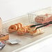 A wire basket with a bagel inside on a hotel buffet counter.