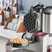 An Estella bubble waffle plate in a waffle maker machine with food on it.