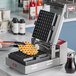 A person using an Estella freestyle plate to make waffles on a waffle maker.