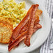 A plate of food with Umaro plant-based vegan bacon, hash browns, and eggs.