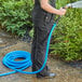 A woman in overalls holding a Lavex blue rubber water hose.