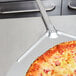 An American Metalcraft Deluxe All Aluminum Pizza Peel with a pizza on a pizza pan.