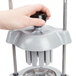 A hand holding a black Vollrath Wedgemaster wedge pusher assembly with round black knobs.