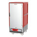 A red and grey metal holding cabinet with wheels.