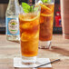 A bottle of Rose's Simple Syrup on a table with two glasses of iced tea with lemons and mint.