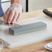 A person using a Choice aluminum oxide knife sharpening stone to sharpen a knife.