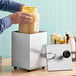 A person using a ServSense stainless steel pump to dispense yellow liquid from a jar.