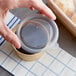 A hand using a Choice plastic lid to cover a container of food.