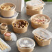 A rectangular Kraft paper take-out container filled with food with a clear plastic lid.