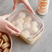 A person holding a rectangular plastic container of food.