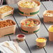 A group of EcoChoice round kraft take-out containers filled with food on a table.