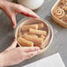 A hand holding a container of churros with a Choice PET lid.