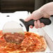 A person using an American Metalcraft stainless steel pizza cutter with a black handle to cut a pizza.