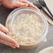 A hand holding a Choice polypropylene lid over a bowl of food.