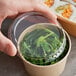 A hand holding a container of seaweed.