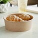 A bowl of croissants in a Choice kraft paper take-out container.