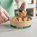 A person putting a pastry into an EcoChoice compostable take-out container.