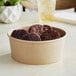 A round brown bowl filled with chocolate cookies on a table.