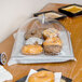 A Carlisle end cut pastry display cover over a tray of donuts on a table.