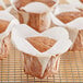 A group of Hoffmaster white lotus baking cups filled with muffins on a cooling rack.