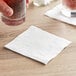 A hand holding a glass of liquid with a white Choice beverage napkin on the table.