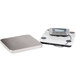 An Edlund stainless steel digital pizza scale on a white surface.