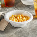 A bowl of macaroni and cheese on a table with a fork.