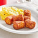 A plate of Stone Gate Breakfast Tater Kegs on a table with a fork and knife.