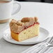 A slice of Hahn's Bakery Raspberry German Crumb Cake on a plate next to a cup of coffee.