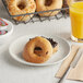 A white plate with two Greater Knead Gluten-Free Cinnamon Raisin Bagels on it next to a glass of orange juice.