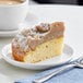 A slice of Hahn's Bakery Traditional German Crumb Cake on a plate next to a cup of coffee.